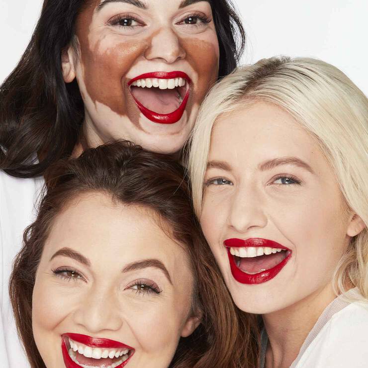 Drei Frauen mit Lippenstift geschminkt lachen in die Kamera
